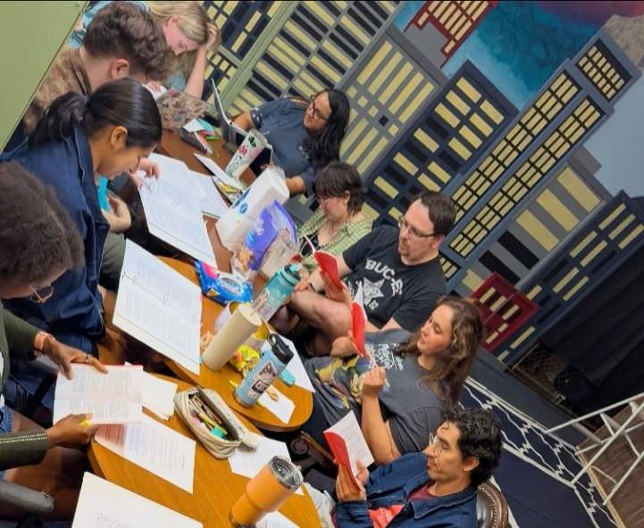 A cast gathers around a table for a script read-through.