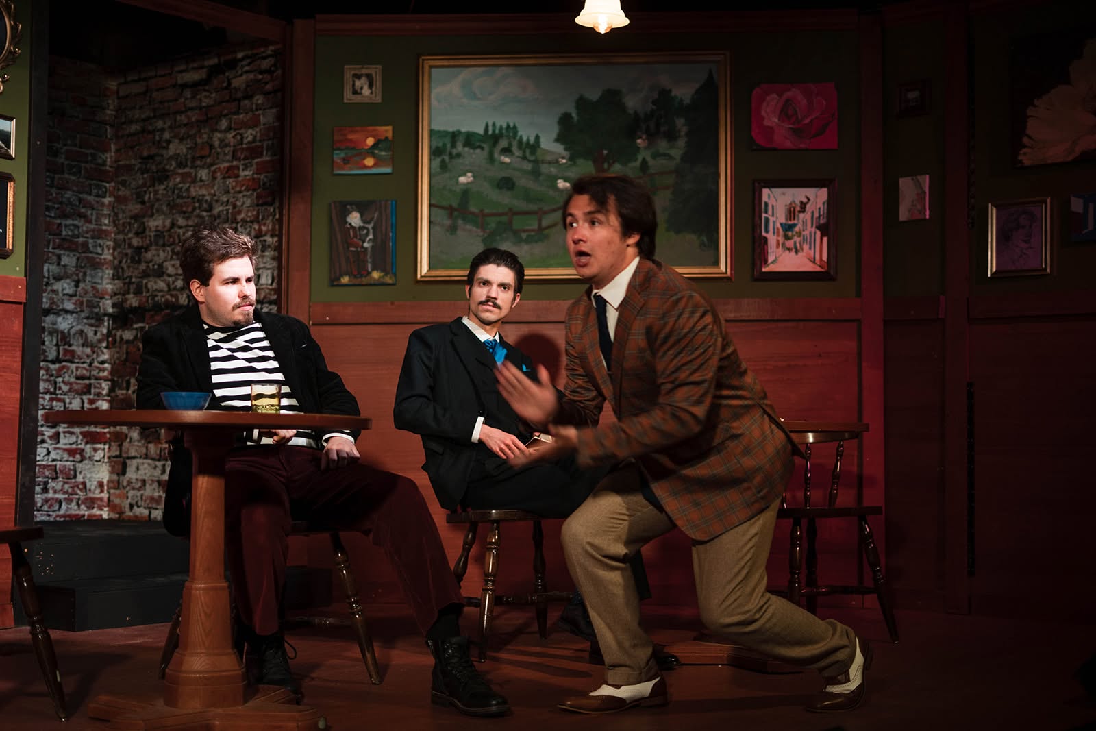 Schmendiman drops to one knee mid-pitch while two men at a cafe table trade skeptical looks.