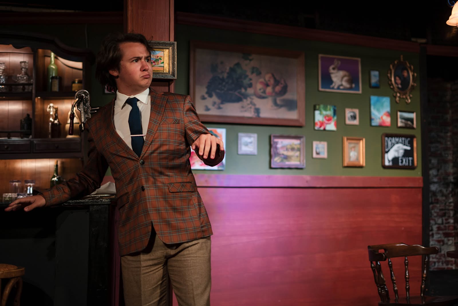 Schmendiman leans on the bar with a doubtful frown, eyeing something across the room.